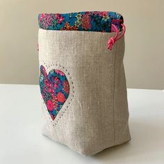 a close up of a bag on a white surface with a flowered heart in the pocket