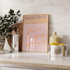 a sign that says guest check next to some other items on a counter with a potted plant