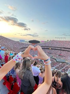 two hands making a heart shape in front of a large crowd at a sporting event