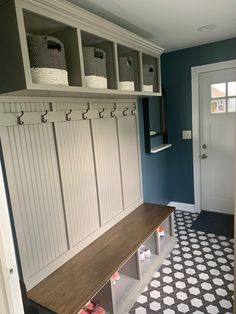 a mudroom with several storage bins on the wall and two benches in front of it