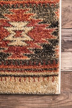 an area rug with various colors and patterns on top of wooden flooring next to a wall