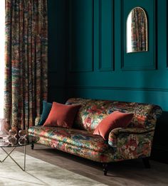 a living room with green walls and floral couch in front of a mirror on the wall