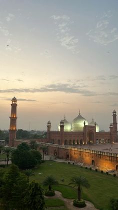 a large building with two towers and lights on it's sides in the evening