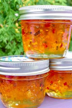 four jars filled with jelly sitting on top of a table