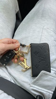 a person is holding a keychain in their lap and it's attached to a purse