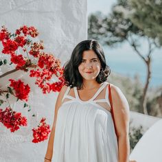 a woman standing in front of red flowers