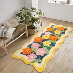 a colorful rug with flowers on the floor in a room next to a chair and potted plant