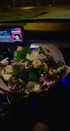 a bouquet of flowers sitting on top of a table in front of a cell phone