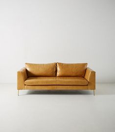 a tan leather couch sitting on top of a white floor