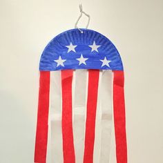 a paper plate shaped like an american flag hanging from a hook on a white wall