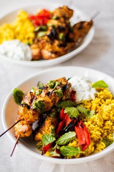 two plates filled with different types of food on top of a white tablecloth covered table