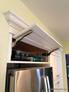 an open shelf above the refrigerator in a kitchen