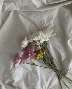 some white and pink flowers are laying on a sheet