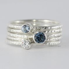 This listing includes 5 Argentium Sterling Silver ring bands, all bands have been given a faceted texture. Argentium silver has a touch of germanium to strongly inhibit tarnish. Argentium 930 silver, is never less than 93% silver. Two of the bands are topped with a sterling silver tube setting and a 3mm gemstone of your choice, the center band includes a 4mm gemstone and the other 2 bands are without gemstone. These skinny rings measure 1.3mm per band. Please contact me if you would like a diffe Diamond Stackable Rings For May Birthstone, Diamond Stackable Rings With May Birthstone, Anniversary Stackable Diamond Rings With Birthstone, Silver Stackable Diamond Rings With Birthstone, Silver Diamond Stackable Rings With Birthstones, Adjustable White Gold Stackable Rings With Birthstone, Stackable Diamond Birthstone Rings With Round Cut, Diamond Stackable Rings With Birthstone, Diamond Birthstone Stackable Rings With Round Cut