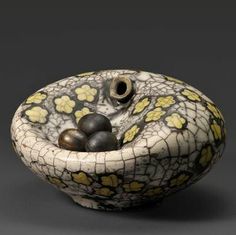 a bowl with two balls in it on a gray surface and yellow flowers around the base