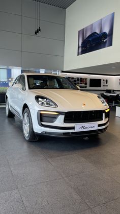 a white porsche cayen is parked in a showroom