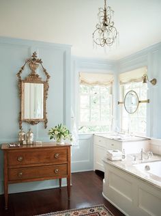 a bathroom with blue walls and wood flooring has a chandelier hanging from the ceiling