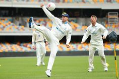 two men in white uniforms are kicking a ball