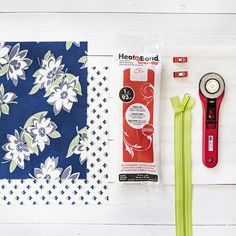 sewing supplies laid out on top of a white wooden table next to a piece of cloth