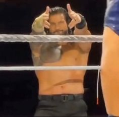 a shirtless man giving the thumbs up sign in front of a wrestling ring net