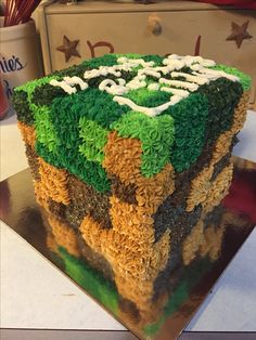 a cake with green and brown frosting sitting on top of a metal platter