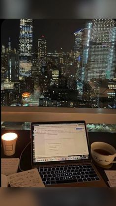 an open laptop computer sitting on top of a desk next to a cup of coffee