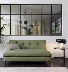 a living room with a green couch and mirror