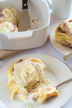 a piece of cake on a plate with a fork next to it and a white container full of icing