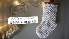 a crocheted christmas stocking hanging on a wall next to a string of lights