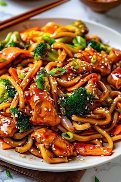 a white plate topped with chicken and broccoli covered in sesame seeds next to chopsticks