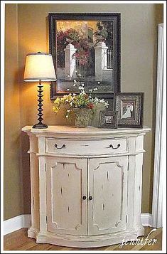 a white cabinet with two pictures on it and a lamp in front of the door