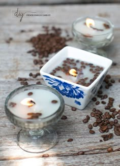 two candles sitting on top of a table next to some coffee beans