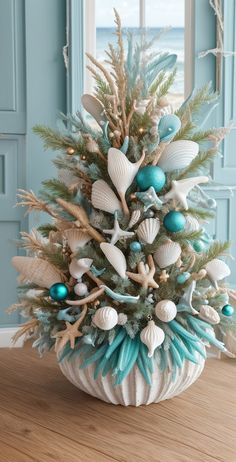 a decorated christmas tree with seashells and starfish on the branches in front of a window