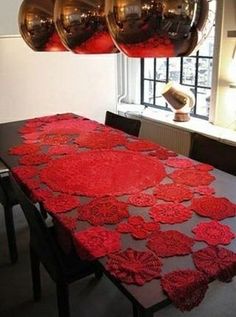 the table is covered with red crocheted doily and has three large shiny balls hanging from it