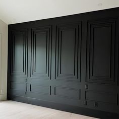 an empty room with black painted walls and wood flooring on the side, in front of a window