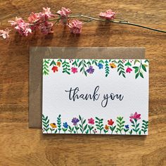 a thank you card with flowers and leaves on the table next to it is an envelope that says, thank you