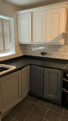 a kitchen with white cabinets and black counter tops