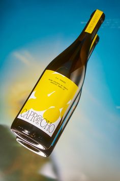 a bottle of wine hanging from the side of a glass table with blue sky and clouds in the background