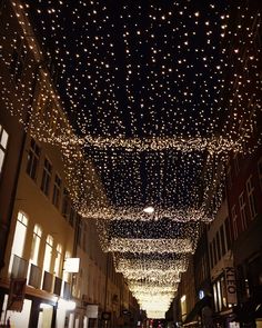 an empty city street is lit up with christmas lights