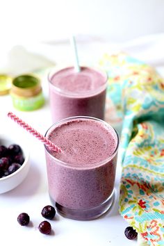 two glasses filled with blueberry smoothie on top of a table