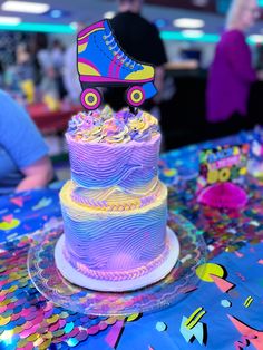 a colorful cake with roller skates on it sitting on top of a table covered in confetti