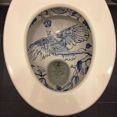 a white toilet with a blue and white bird design on the lid, in a bathroom