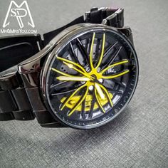 a watch with yellow and black wheels on it's face sitting on the floor