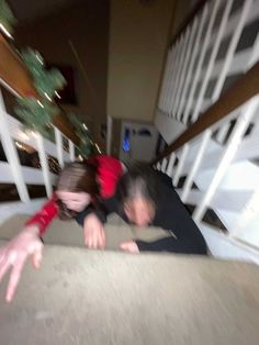 two people laying down on the ground in front of stairs with their hands out to touch each other