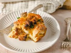 a white plate topped with an egg casserole next to a fork and knife