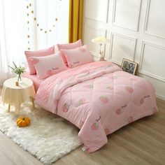 a bed with pink comforter and pillows in a room next to a white rug