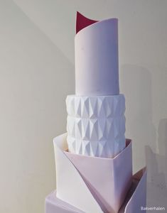 a three tiered white and red cake with geometric designs on it's sides