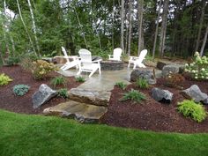 an outdoor patio with chairs and rocks in the foreground, surrounded by green grass