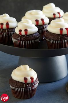 chocolate cupcakes with white frosting and cranberry toppings on a black cake stand