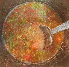 a wooden spoon in a pot filled with soup and vegetable stew, ready to be cooked